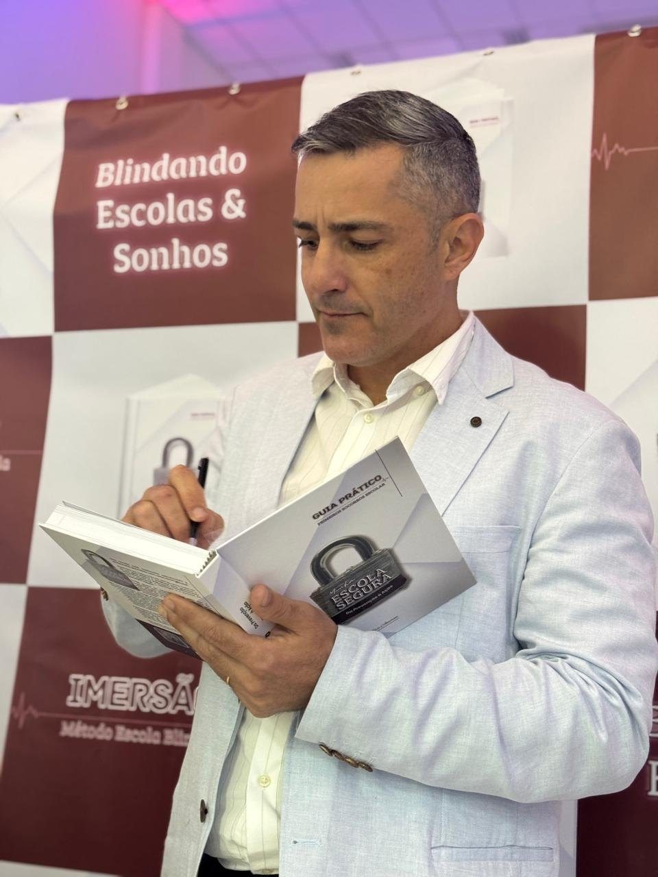 Eric Amorim com o Guia Prático Minha Escola Segura no palco da imersão